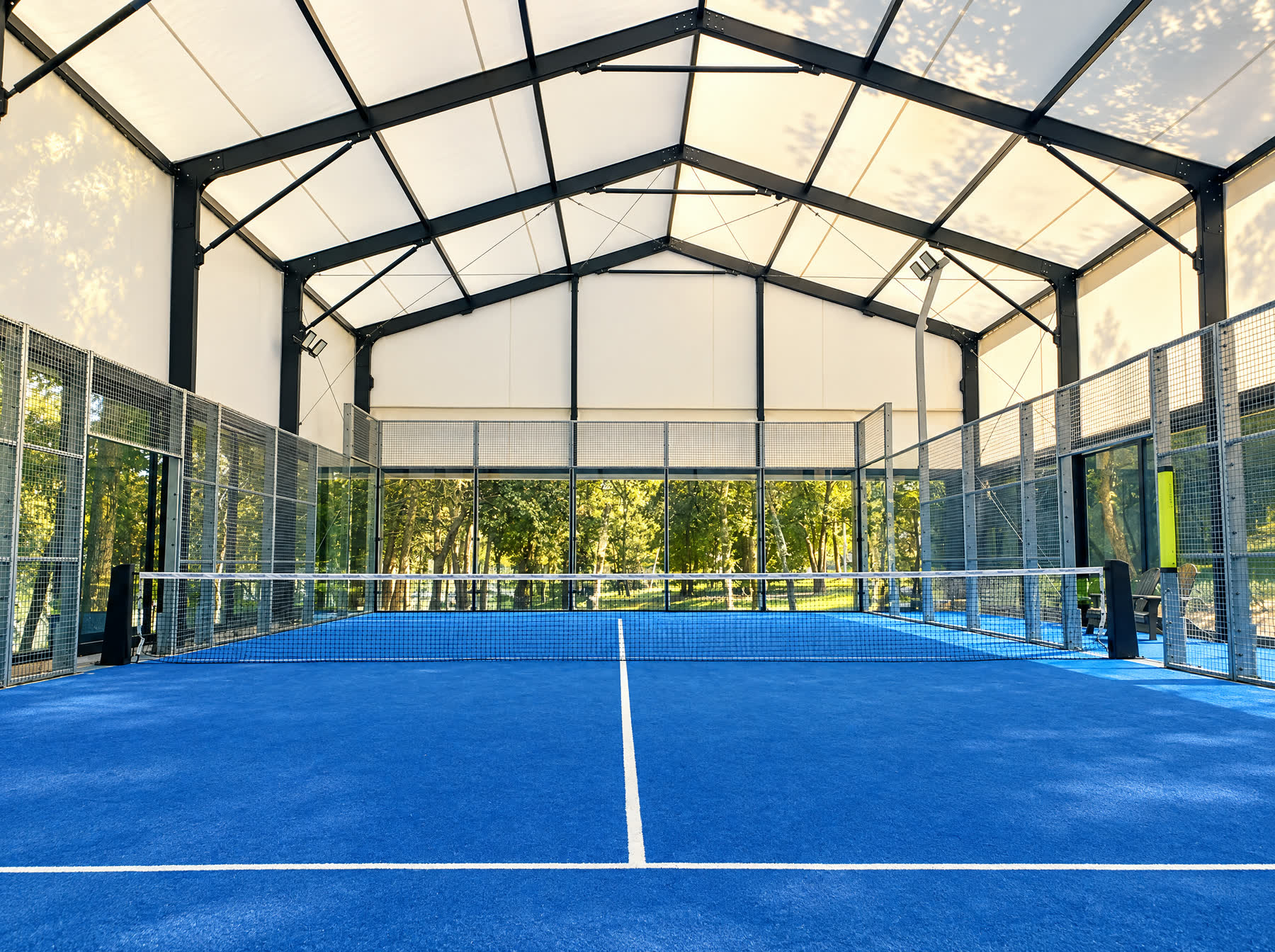 Four padel courts under a white tensile canopy